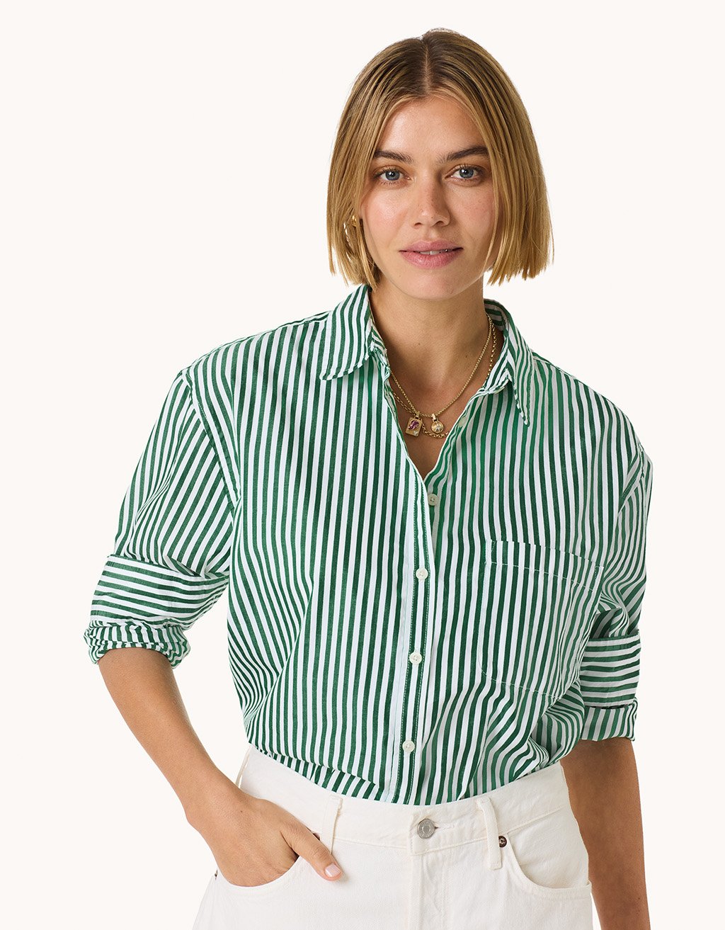 Woman wearing a green and white striped button down shirt on a light gray background