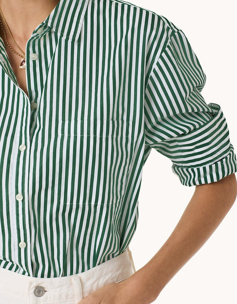 Close-up of a green and white striped shirt with rolled-up sleeves on a person against a white background