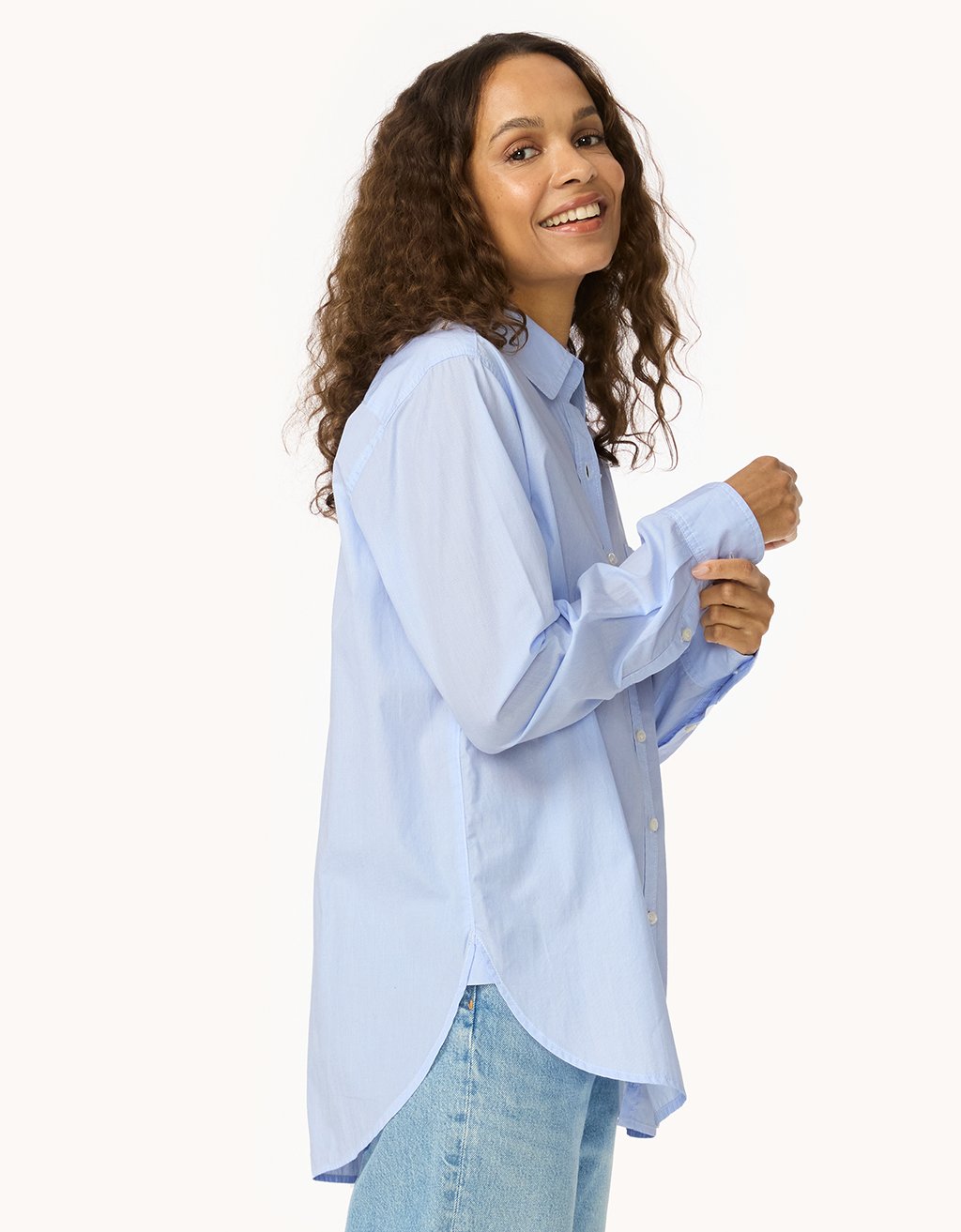 Profile of a woman wearing a light blue shirt and jeans on a white background