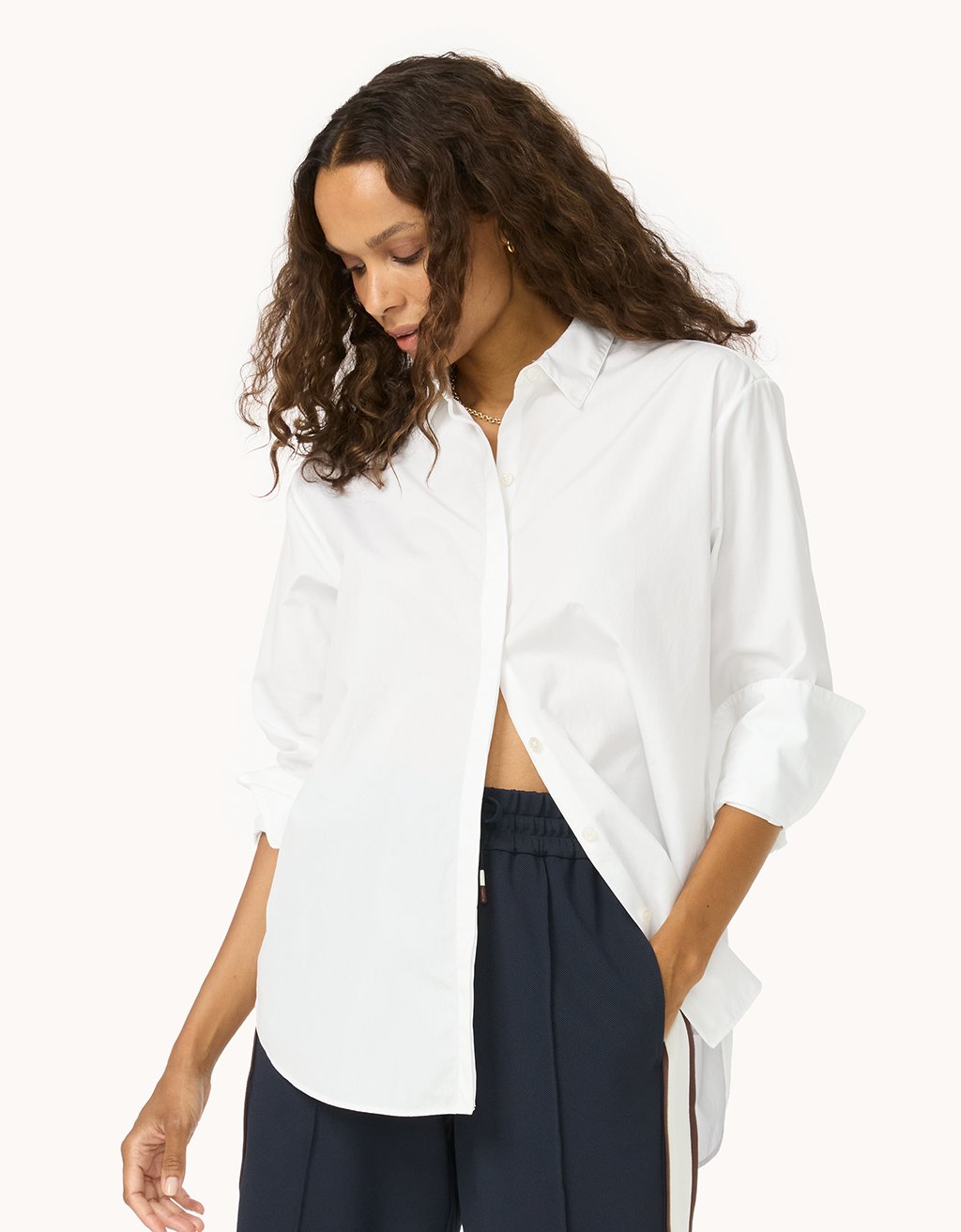Woman wearing a white button down shirt and navy pants on a white background