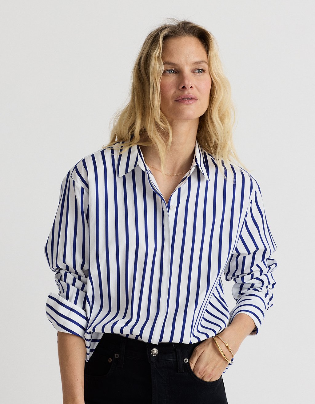 Woman wearing a cobalt blue and white striped button down shirt against a plain background