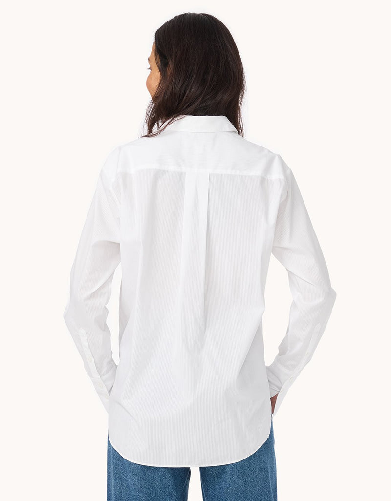 Back view of a woman wearing a white shirt and blue jeans on a white background