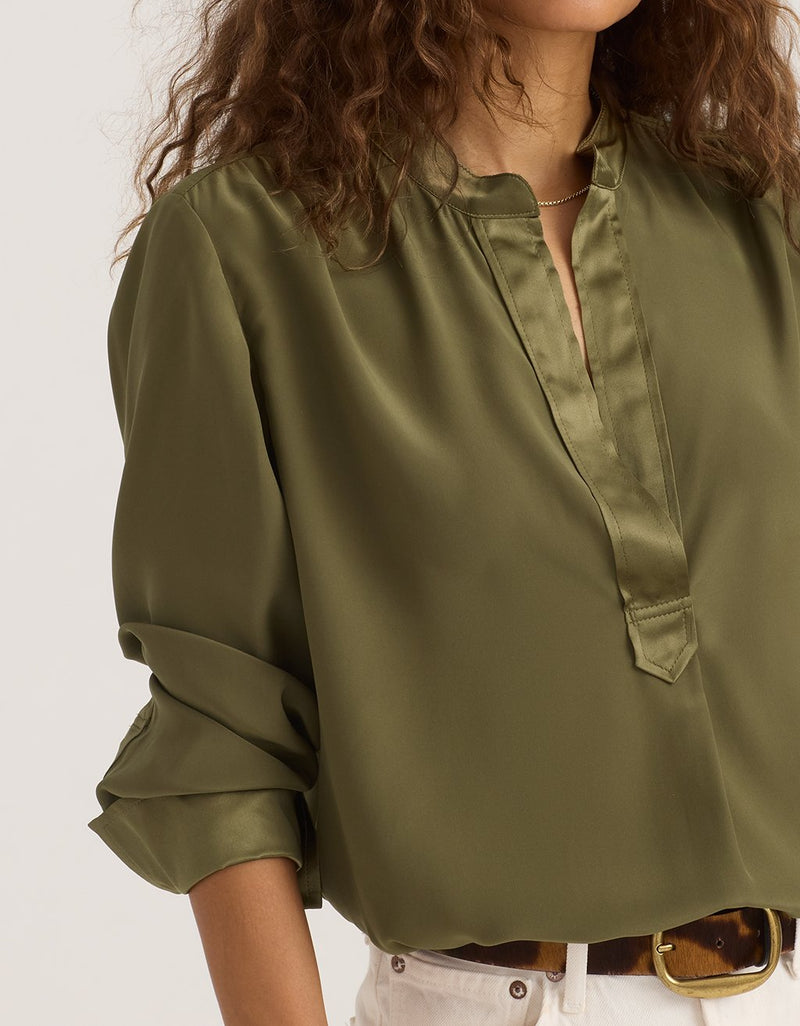 Olive silk blouse worn by a woman on a white background