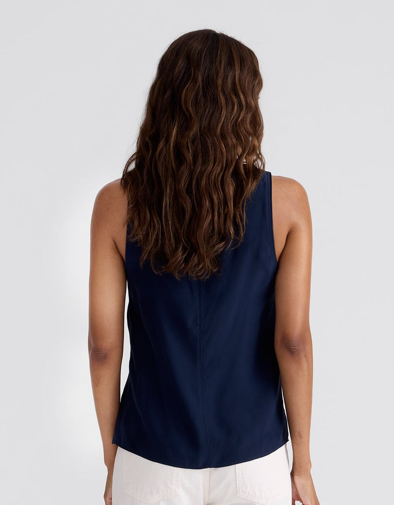 Woman wearing a navy blue tank top and pants on a light gray background