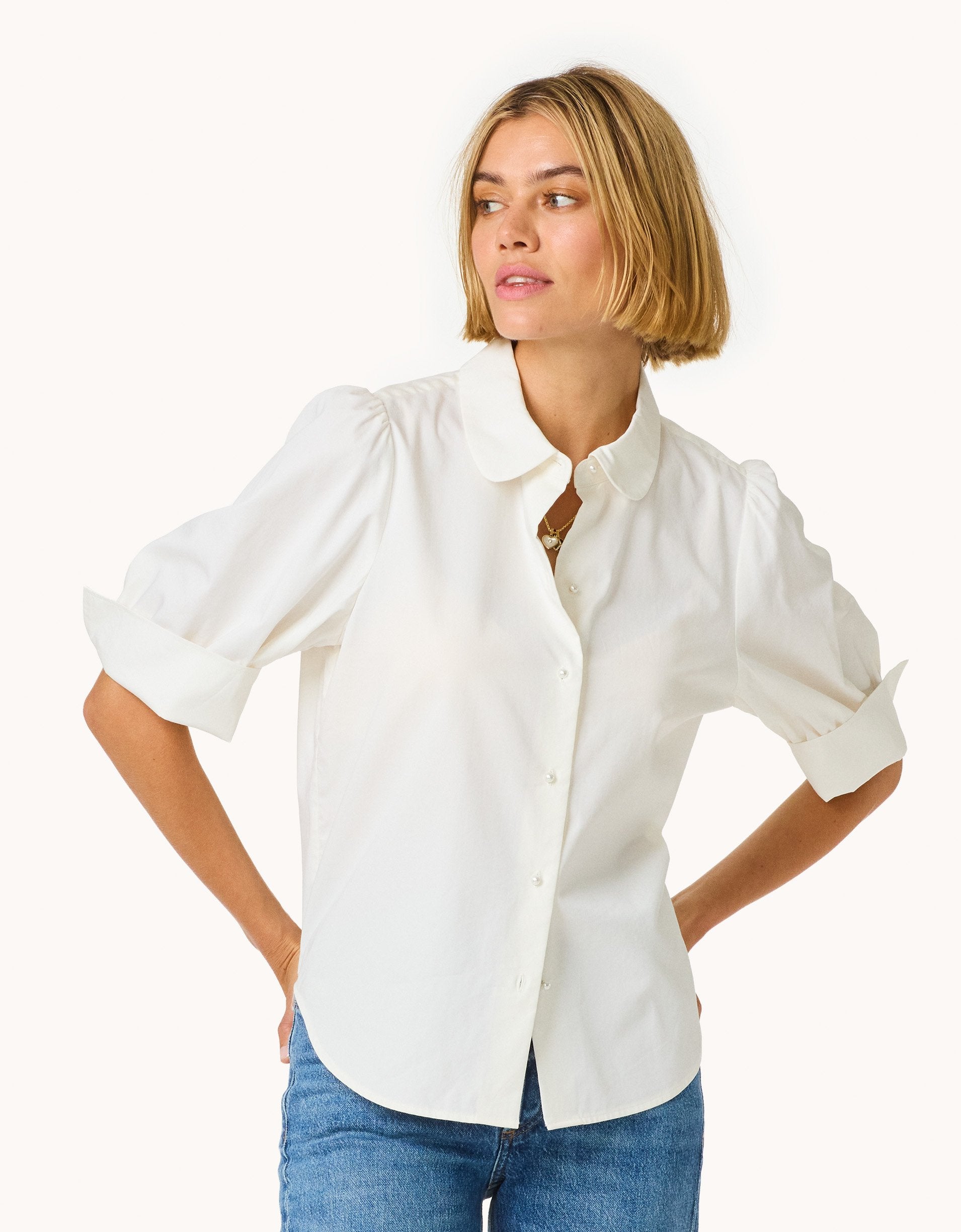 Woman wearing a puff sleeve button down shirt on a plain background
