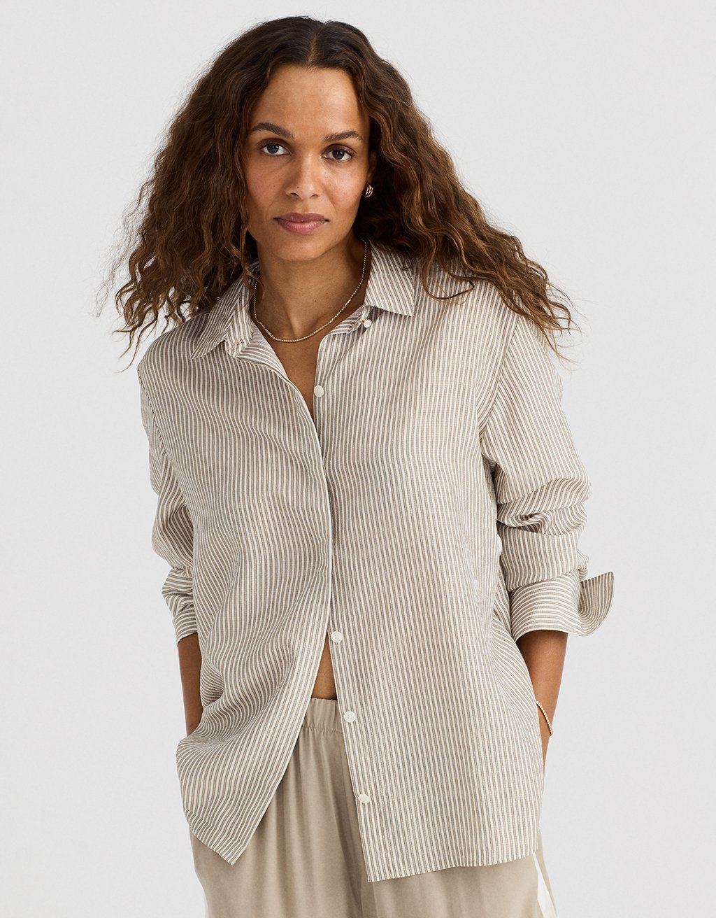 Woman wearing a beige striped shirt and pants on a white background