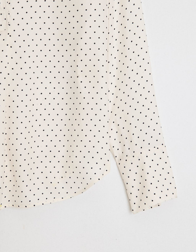 Close-up of a white fabric with black polka dots on a light gray background