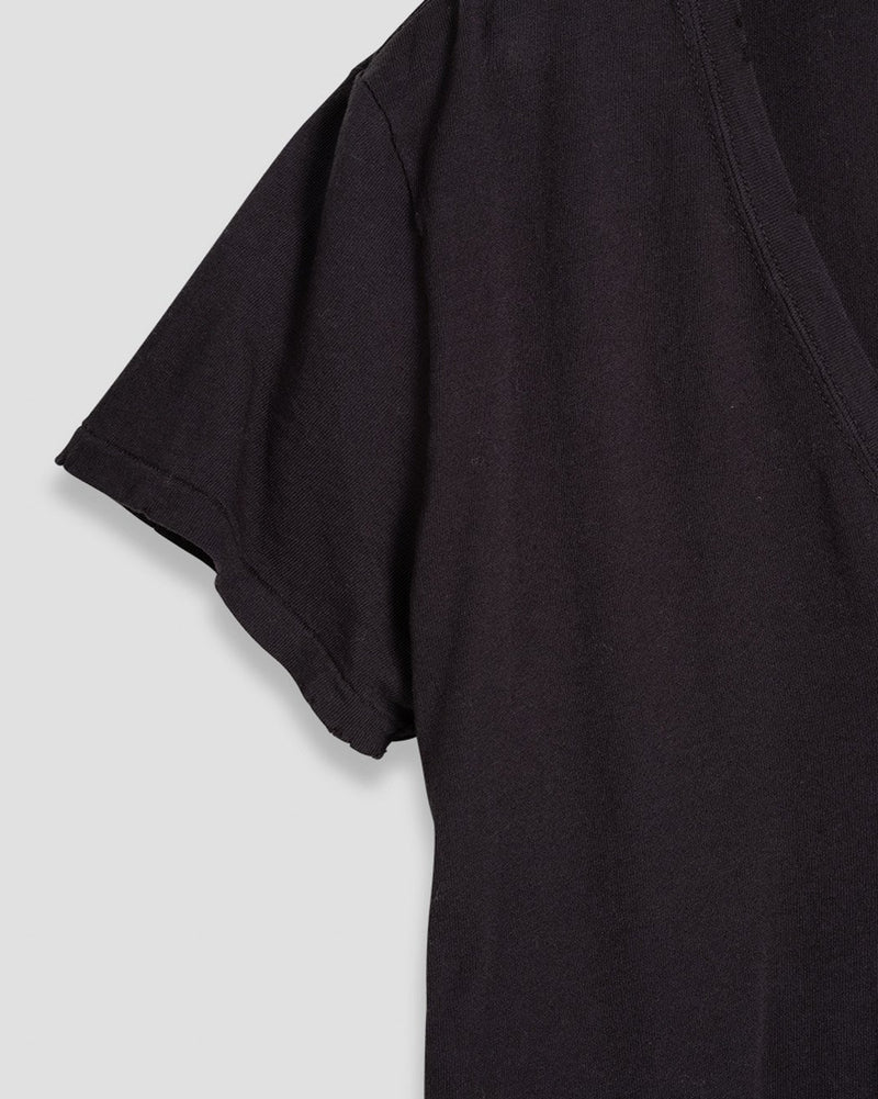 Close up of the sleeve and neckline of a black t-shirt on a light gray background