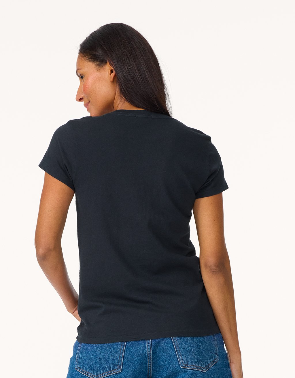 Back view of a woman wearing a black t-shirt and blue jeans on a light gray background
