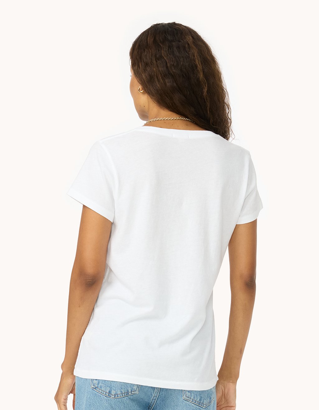 Back view of a woman wearing a white t-shirt and light jeans on a white background