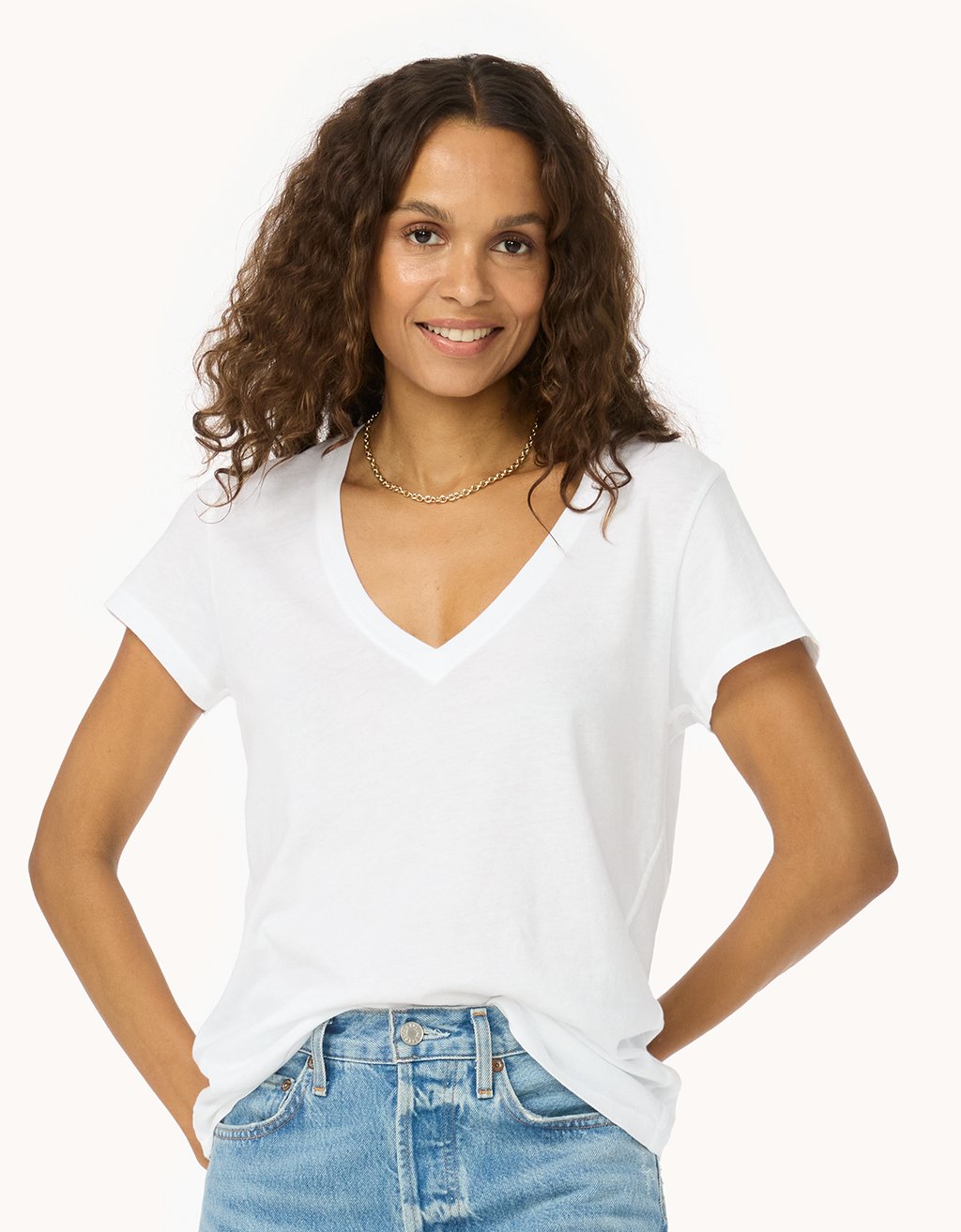 Woman wearing a white V-neck t-shirt and blue jeans on a white background