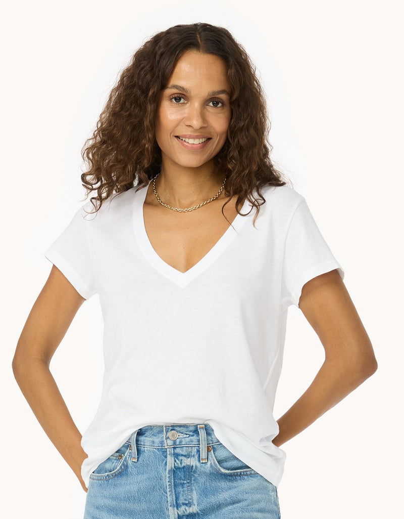 Woman wearing a white V-neck t-shirt and blue jeans on a white background