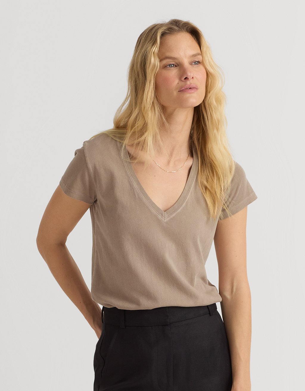 Woman wearing a beige V-neck t-shirt against a plain background