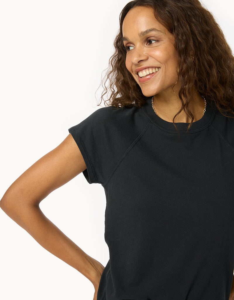 Woman wearing a black raglan t-shirt against a white background