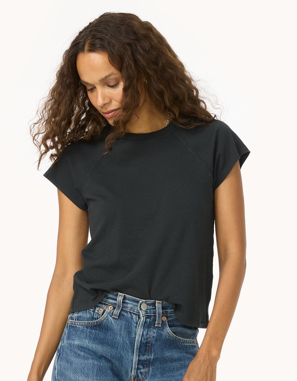 Woman wearing a black raglan t-shirt and blue jeans on a white background