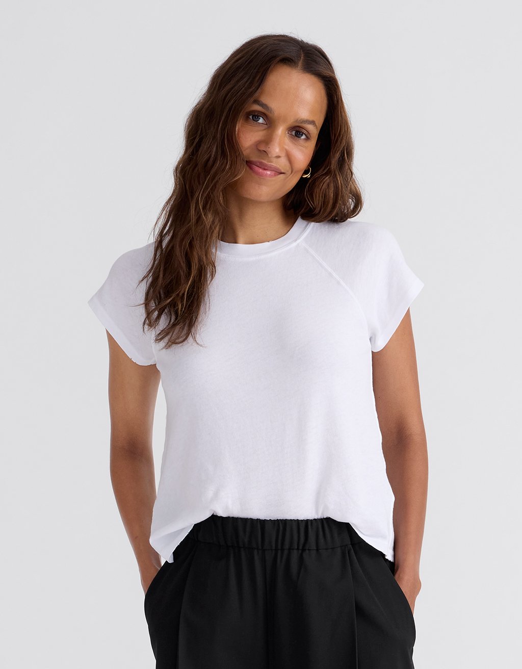Woman wearing a white raglan t-shirt and gray pants on a white background