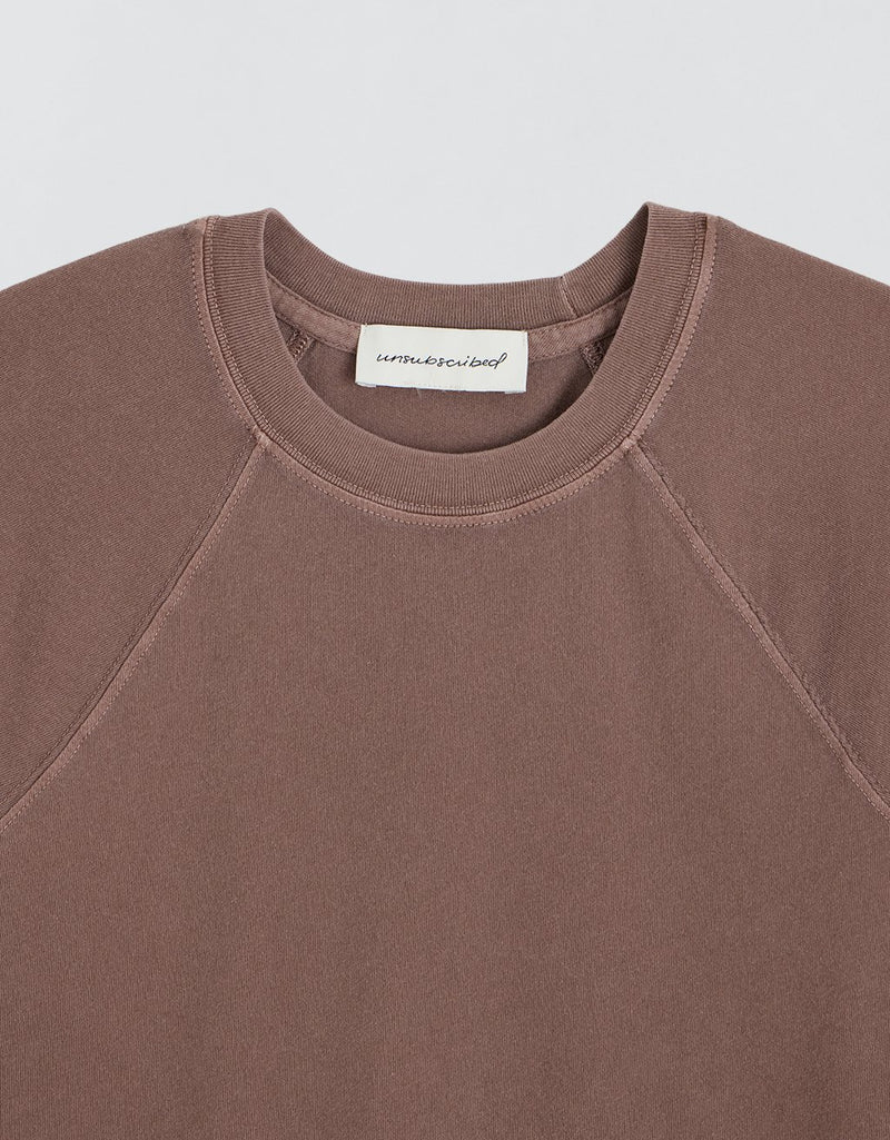 Brown t-shirt with a visible brand label on a light gray background