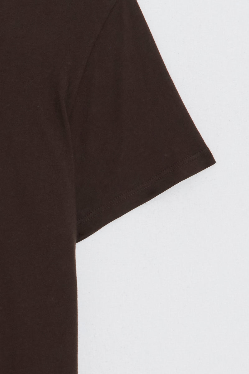 Close up of the sleeve of a brown t-shirt on a light gray background
