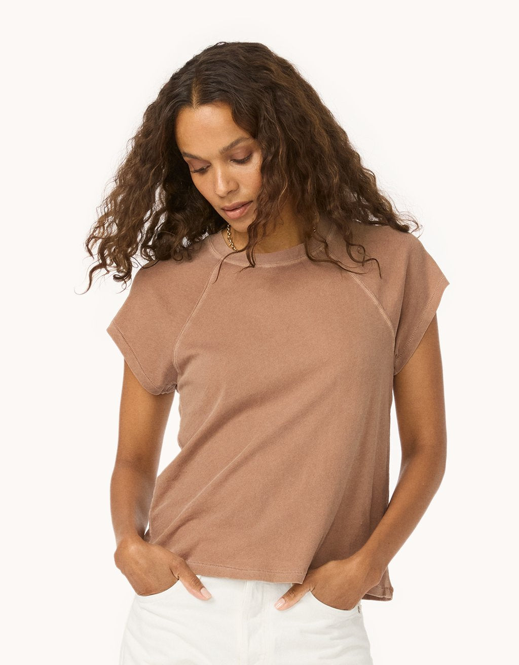 Woman wearing a cappuccino brown raglan t-shirt and white jeans against a white background