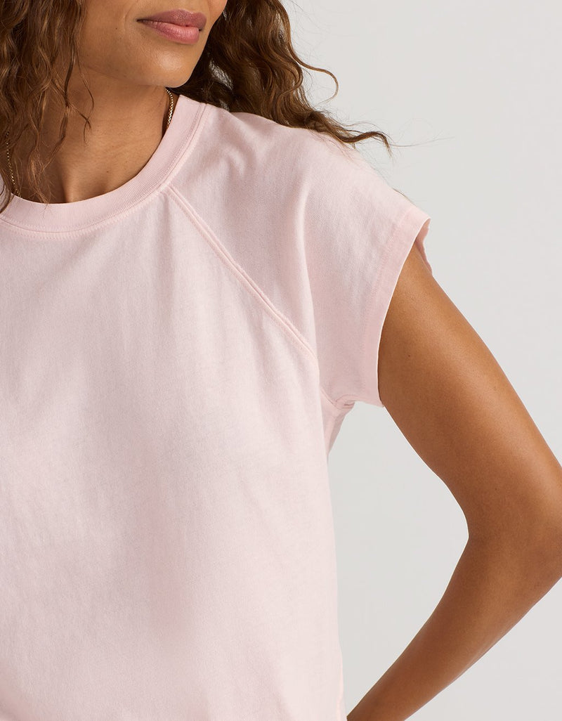 Close-up of a woman wearing a light pink t-shirt against a neutral background