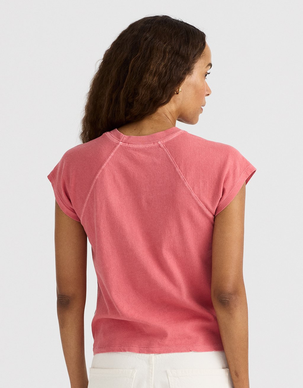 Woman wearing a brick red raglan t-shirt on a light gray background