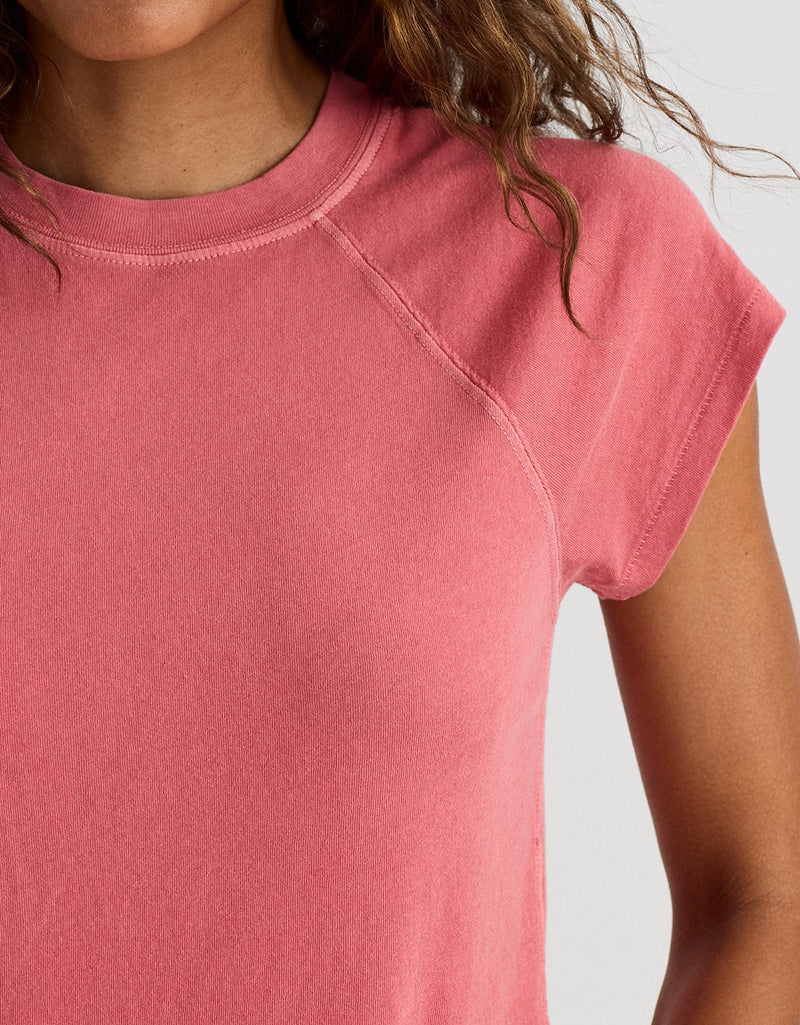 Close-up of a woman wearing a brick red raglan t-shirt against a light gray background