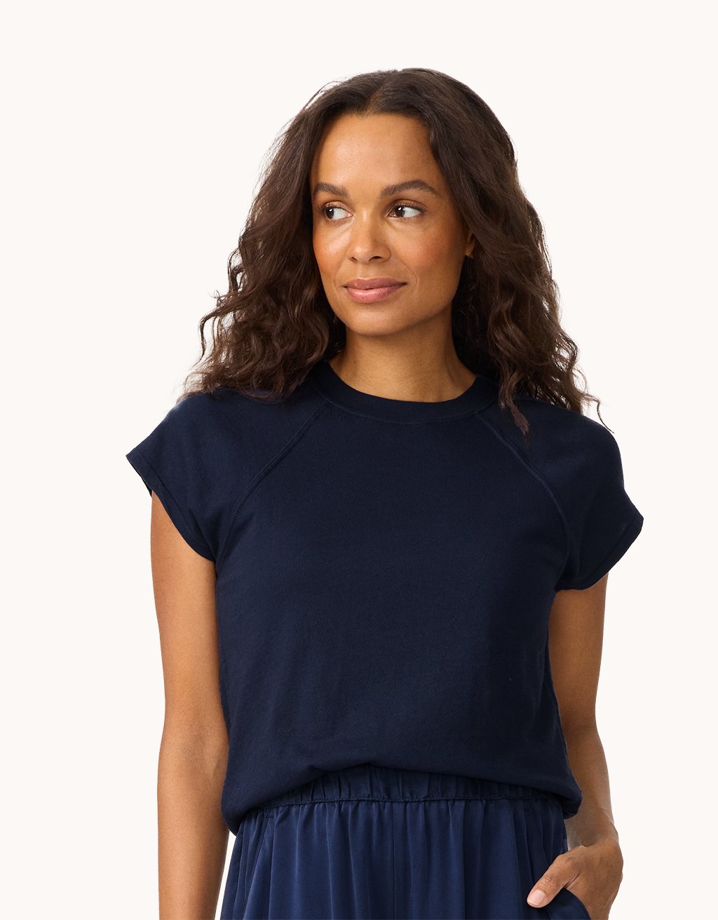Woman wearing a navy blue raglan t-shirt and skirt on a white background
