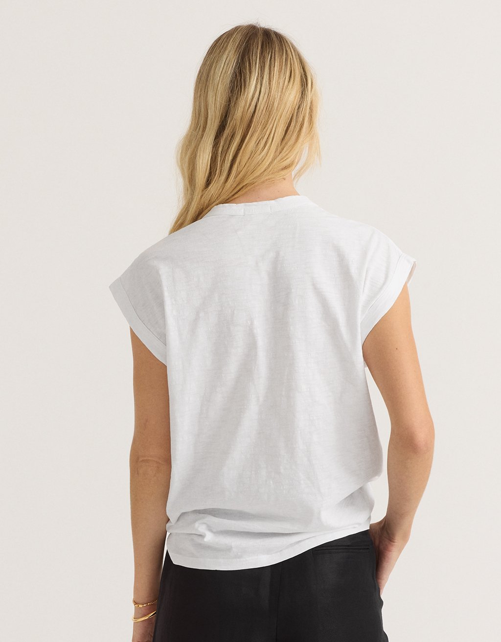 Back view of a woman wearing a white t-shirt on a light gray background