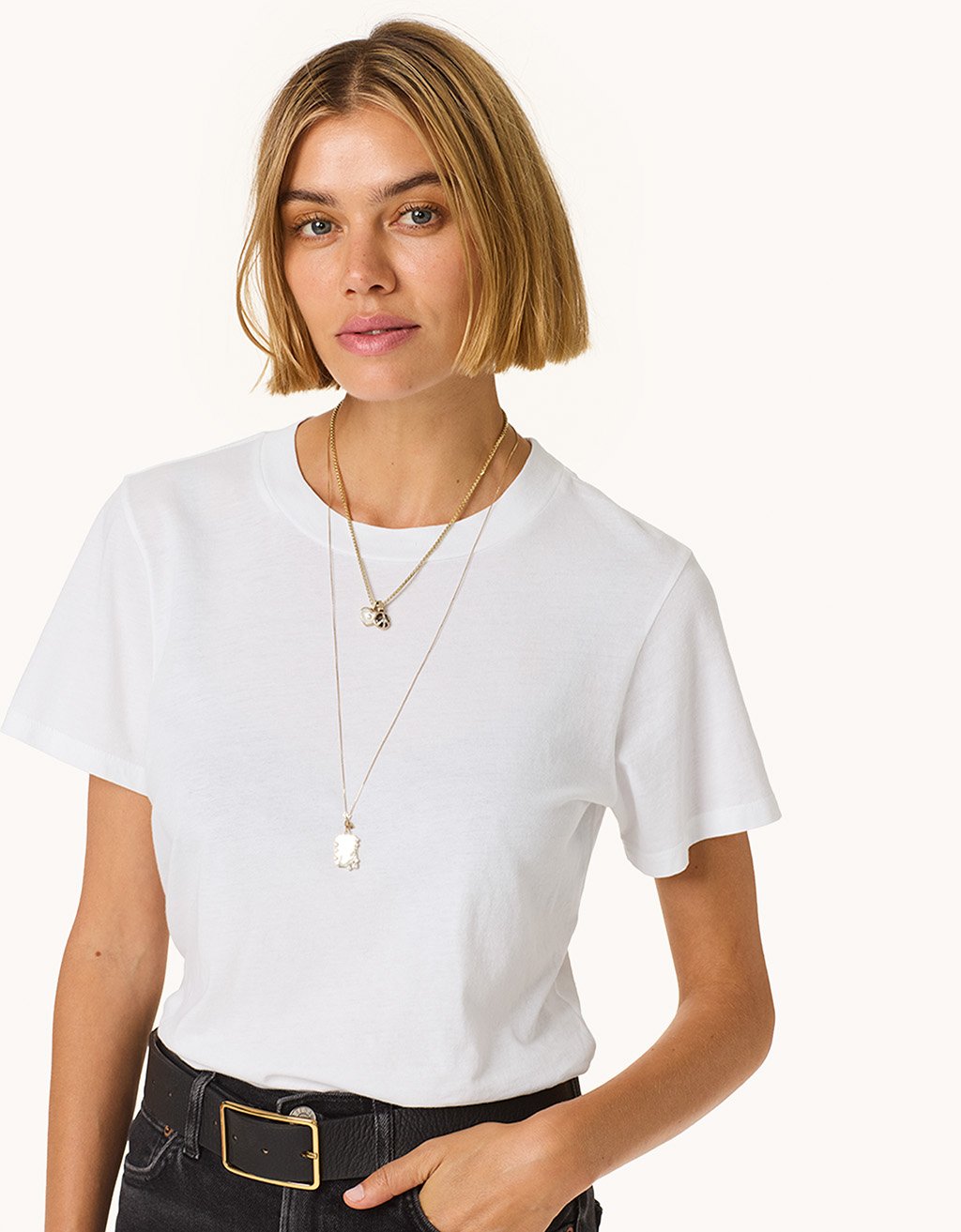 Woman wearing a white t-shirt and black pants with a plain background