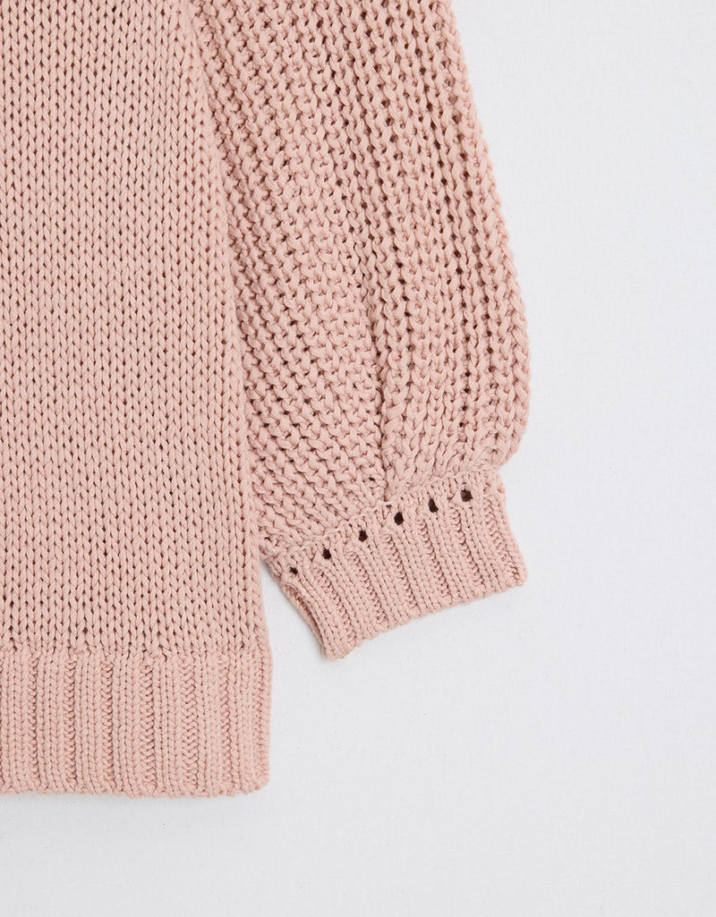 Close-up of a pink sweater sleeve on a light gray background