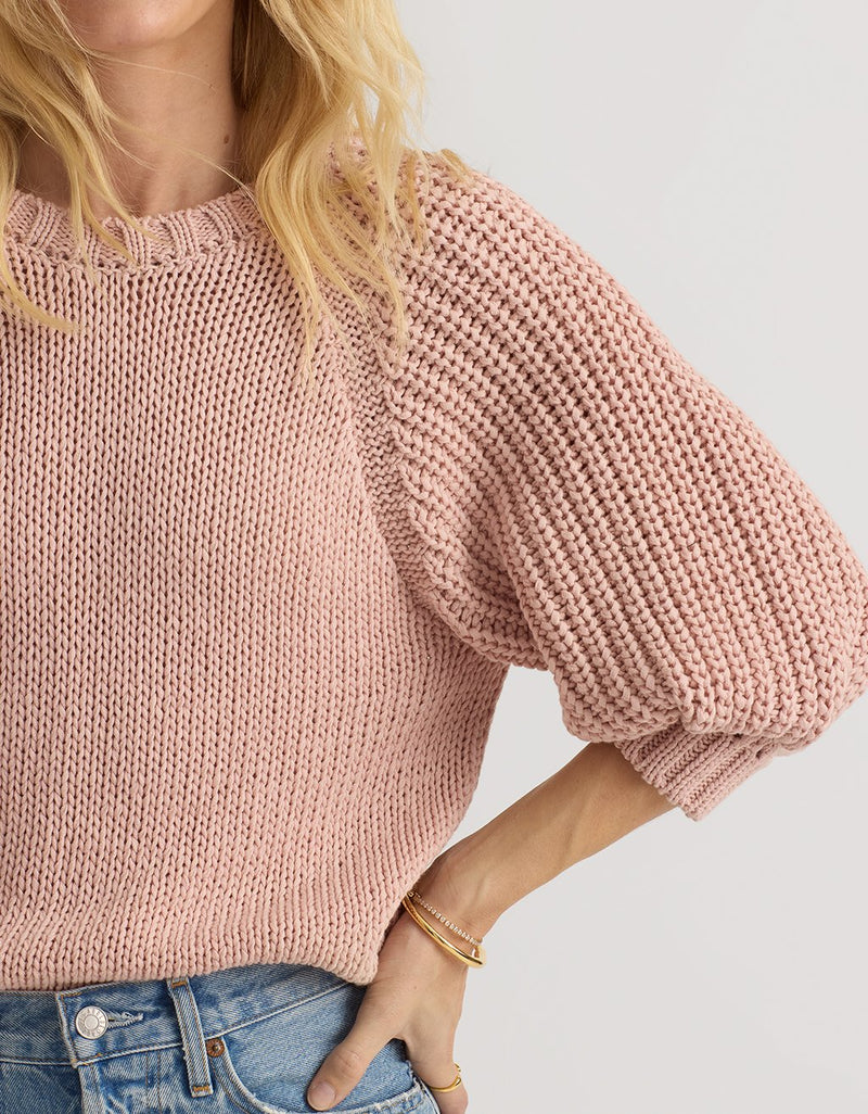 Person wearing a pink puff sleeve sweater with a light gray background