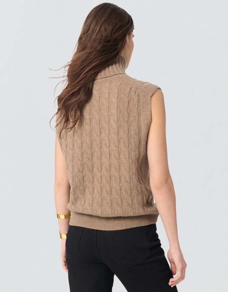 Back view of a woman wearing a camel sleeveless knit turtleneck on a light gray background