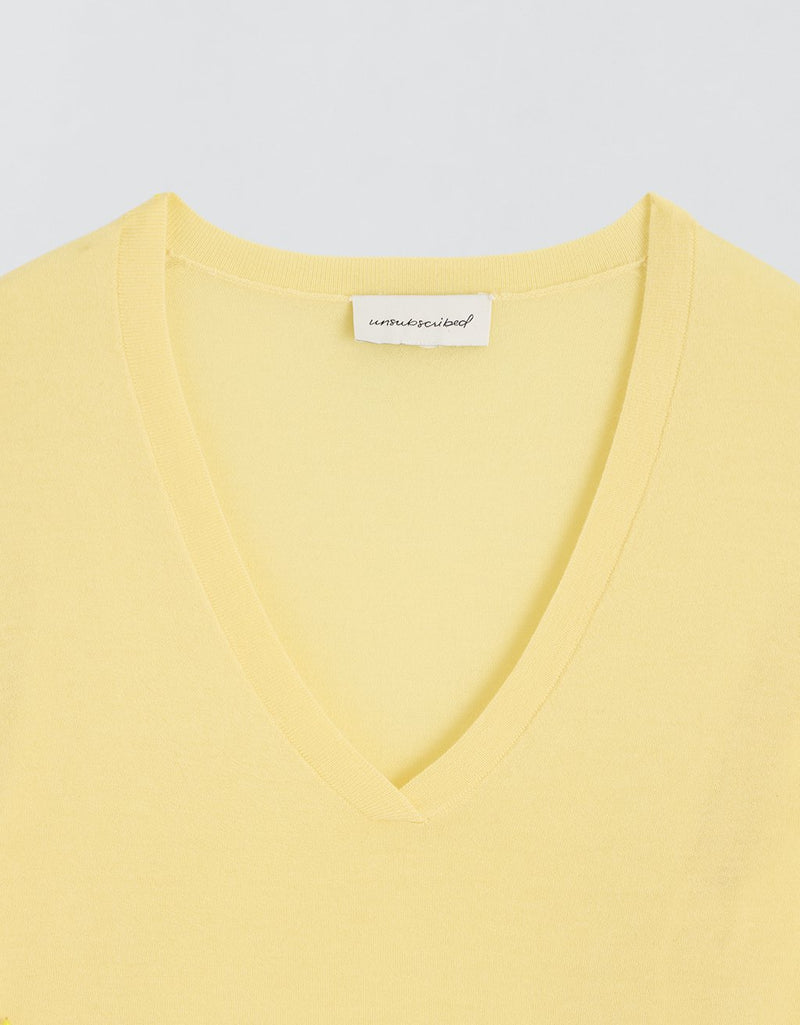 Yellow V-neck cashmere sweater with a brand label on a light gray background