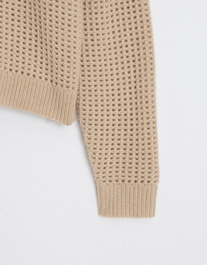 Close-up of a camel open-stitch camel sweater sleeve on a light gray background