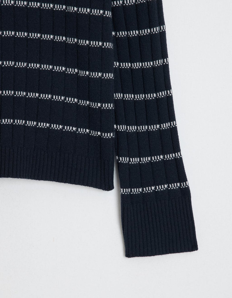Close-up of a navy striped ribbed cashmere sweater on a light gray background
