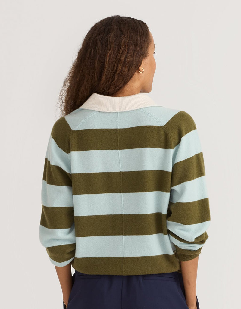 Back view of a woman wearing a green and light blue striped cashmere polo sweater on a plain background