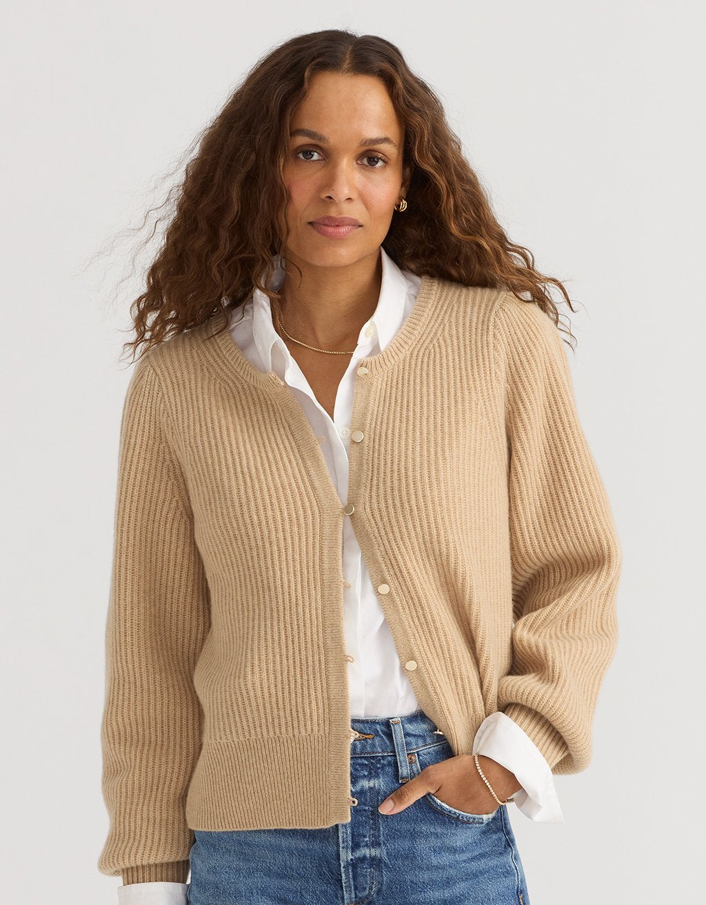 Woman wearing a camel cashmere puff sleeve cardigan over a white shirt with a light gray background