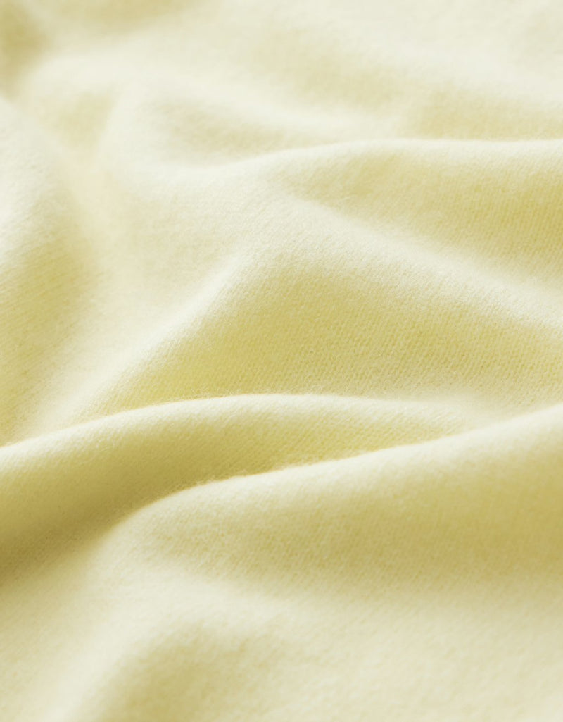Close-up of soft, light yellow cashmere fabric with a subtle texture