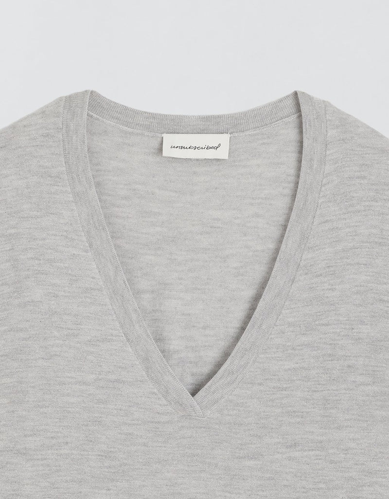 Gray cashmere sweater with a deep V-neck and brand label on a light gray background