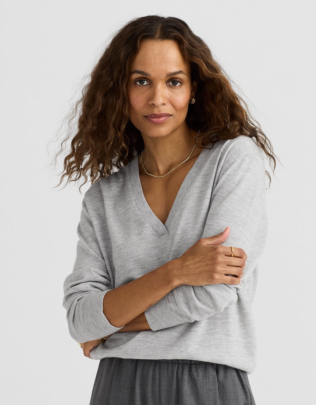 Woman wearing a V-neck gray cashmere sweater against a light gray background