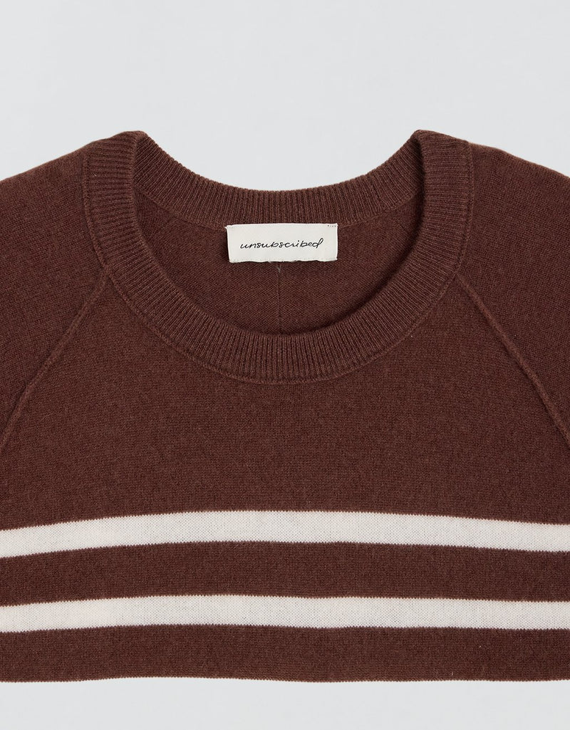 Ribbed neckline of a brown cashmere sweater with white stripes and a visible brand label on a light gray background