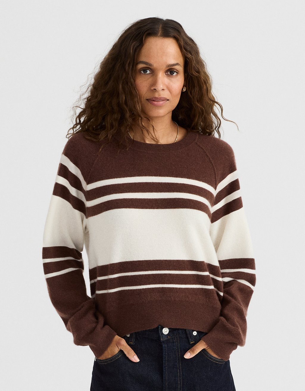 Woman wearing a brown and white striped cashmere sweater on a plain background