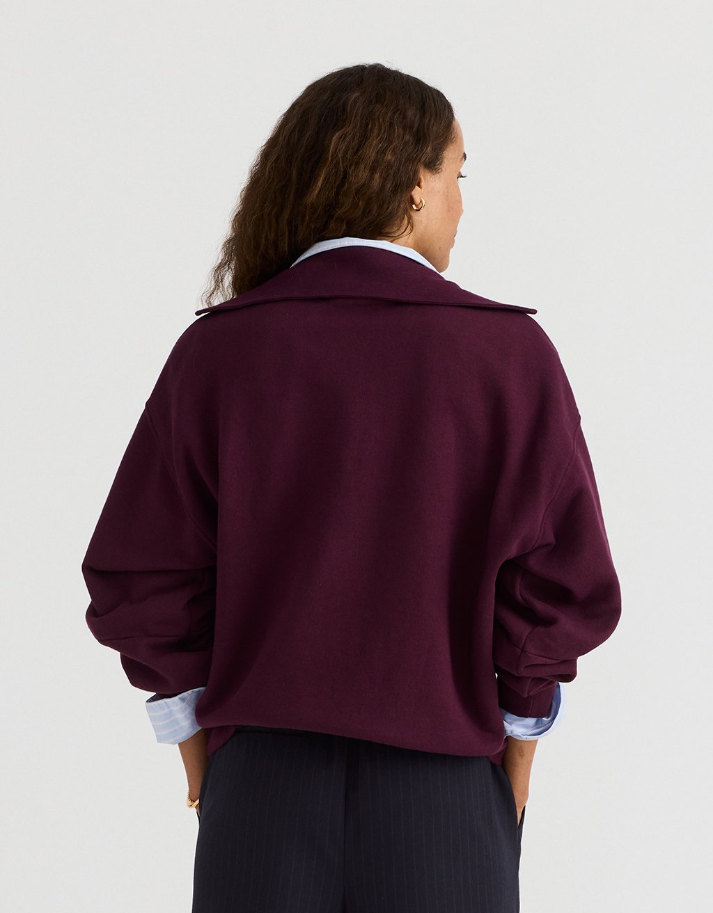 Woman wearing a burgundy polo sweatshirt on a plain background