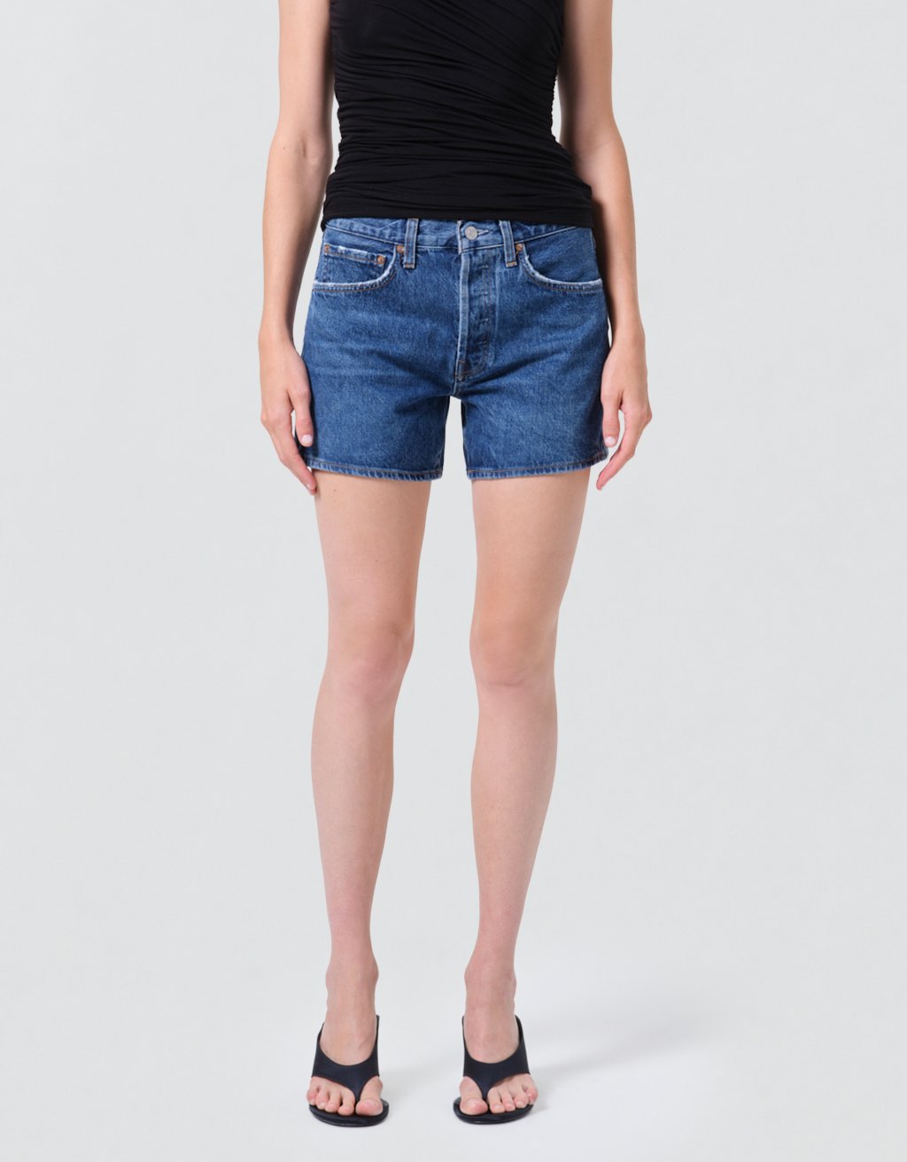 Person wearing high-rise blue denim shorts on a plain background