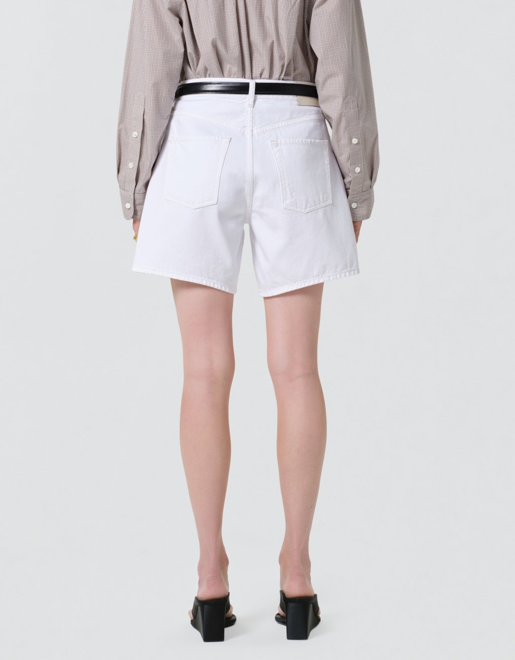 Person wearing a beige shirt and white shorts on a plain background