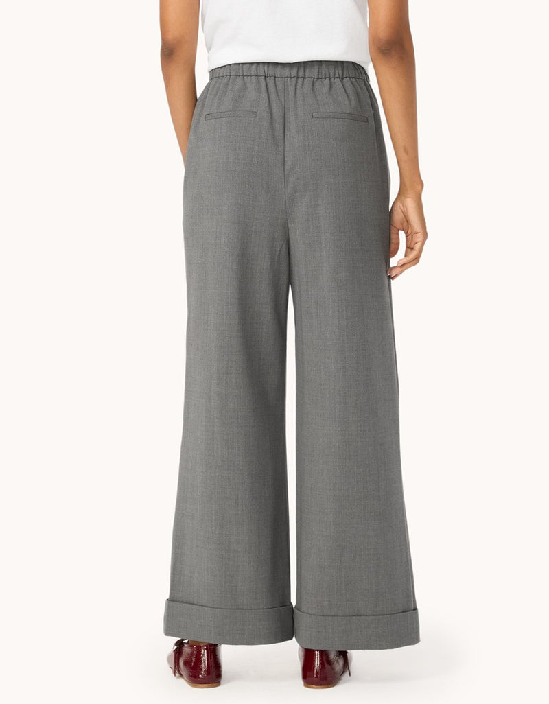 Back view of gray wide-leg pants worn by a person on a light gray background
