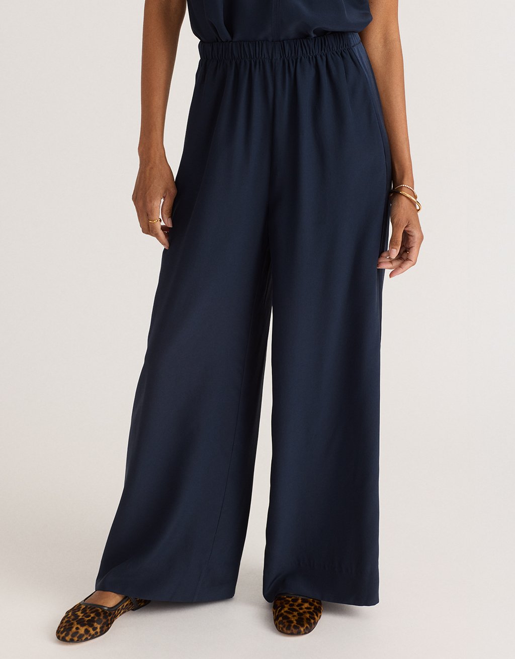 Navy blue wide leg pants worn by a person on a light gray background