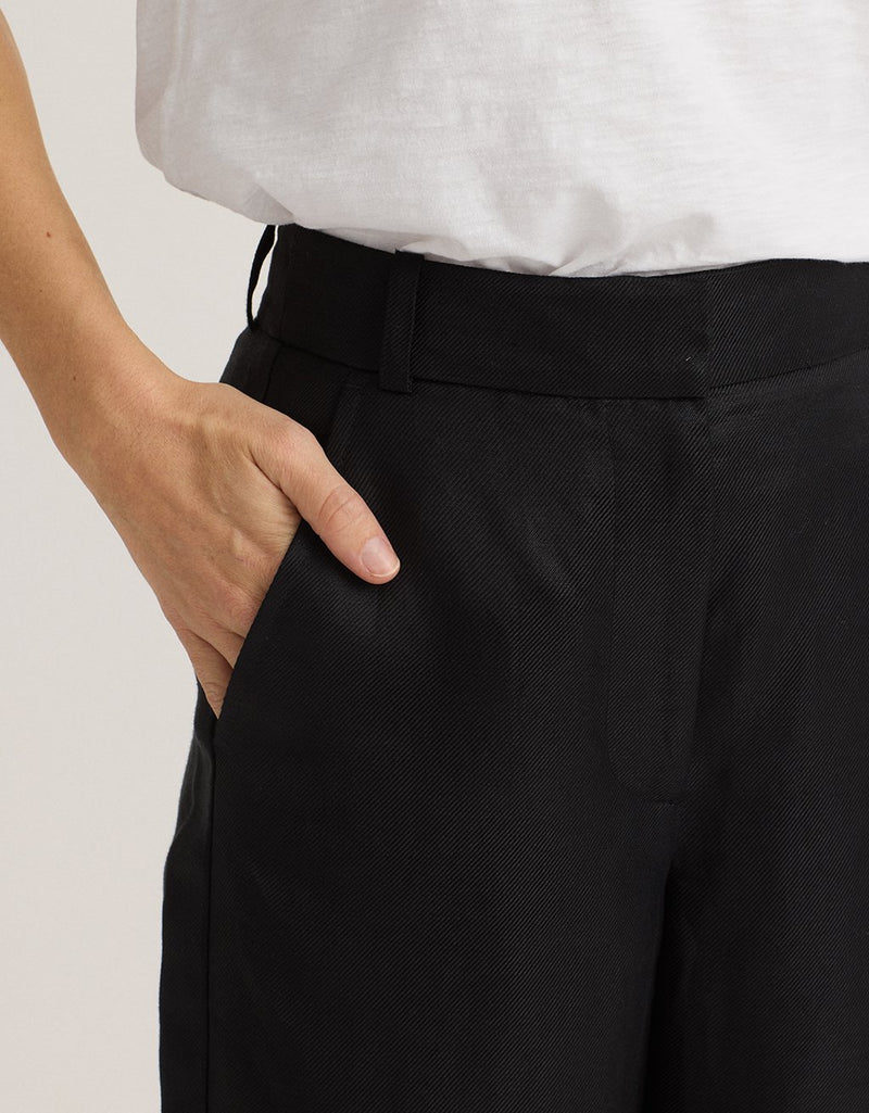Close-up of black pants and a white t-shirt with a neutral background