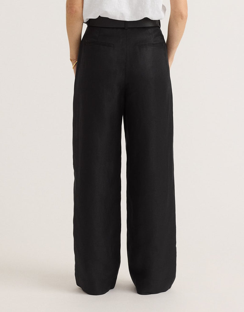 Back view of woman wearing black wide-leg pants on a plain background