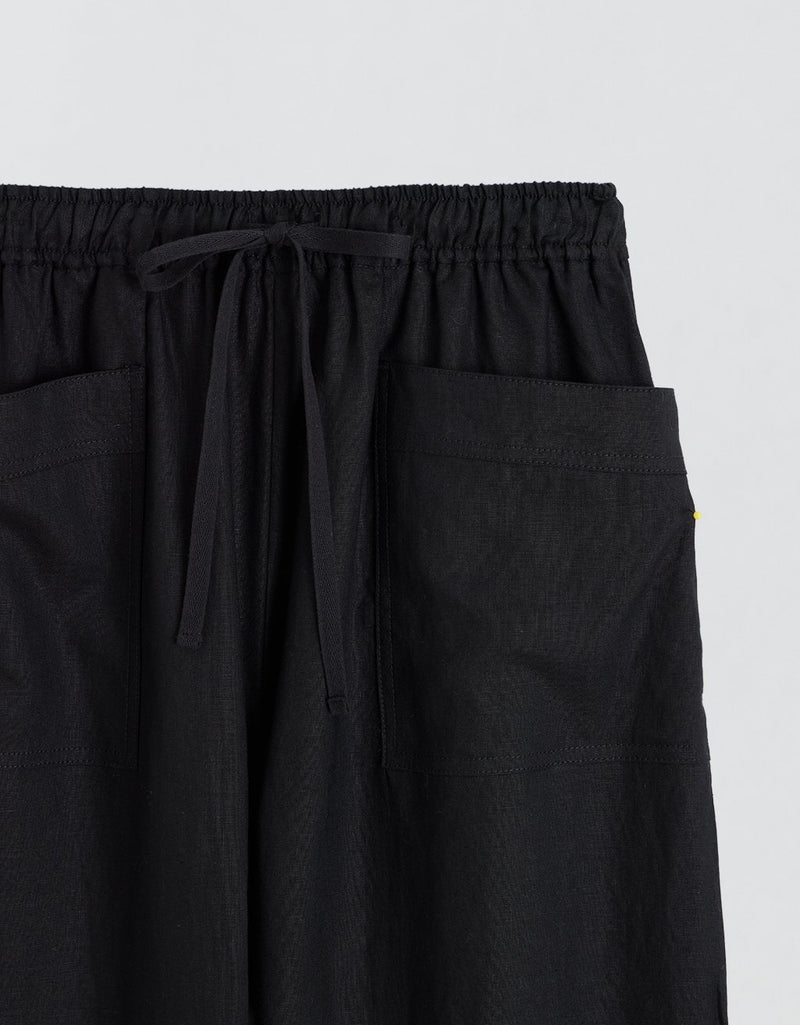 Close up of black pants with drawstring waistband and front pockets on a light gray background